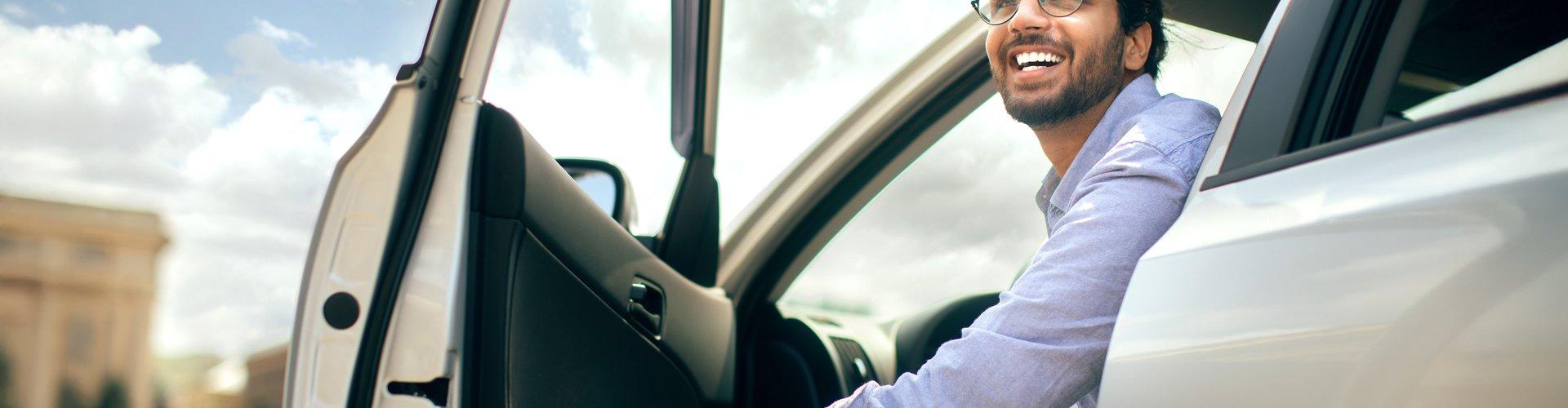 Maennlicher  Fahrer öffnet die Autotuer.