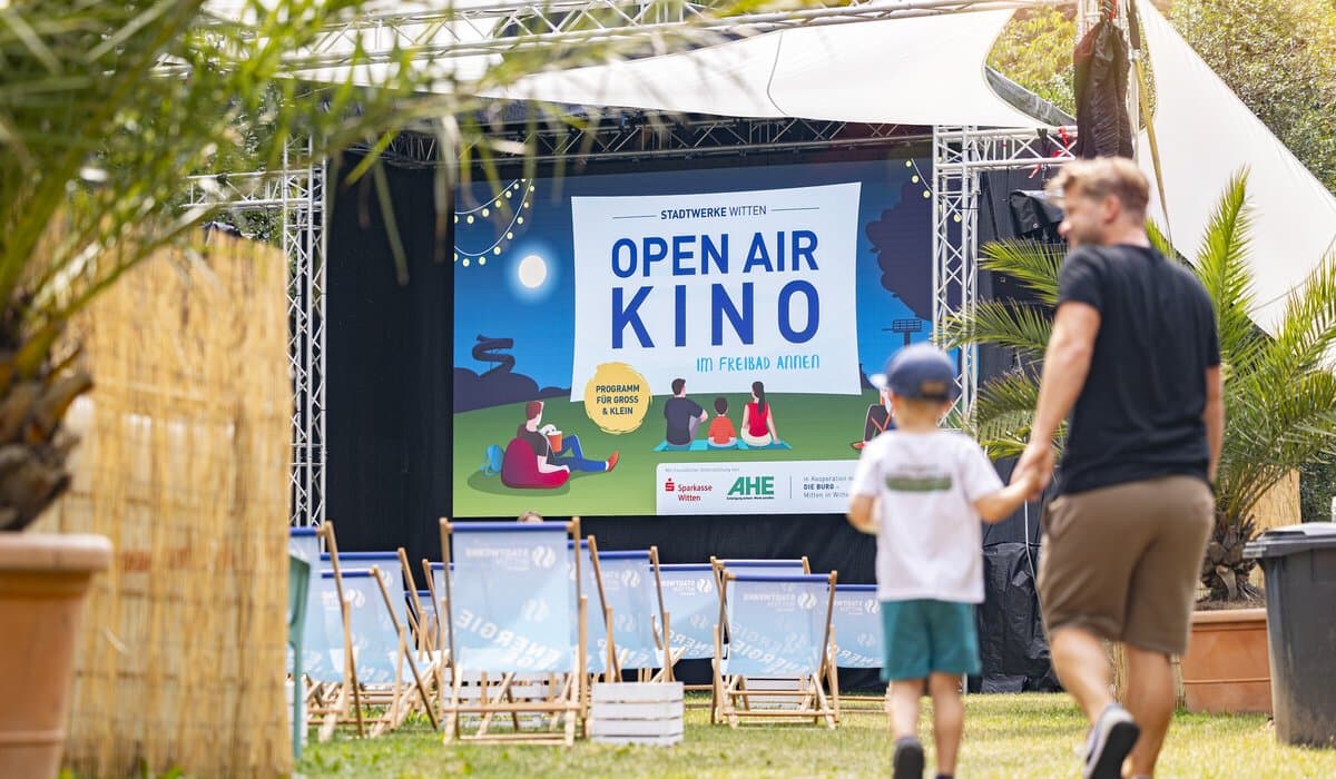 Vater und Sohn laufen zu den Liegestühlen vor der Bühne des Open Air Kinos