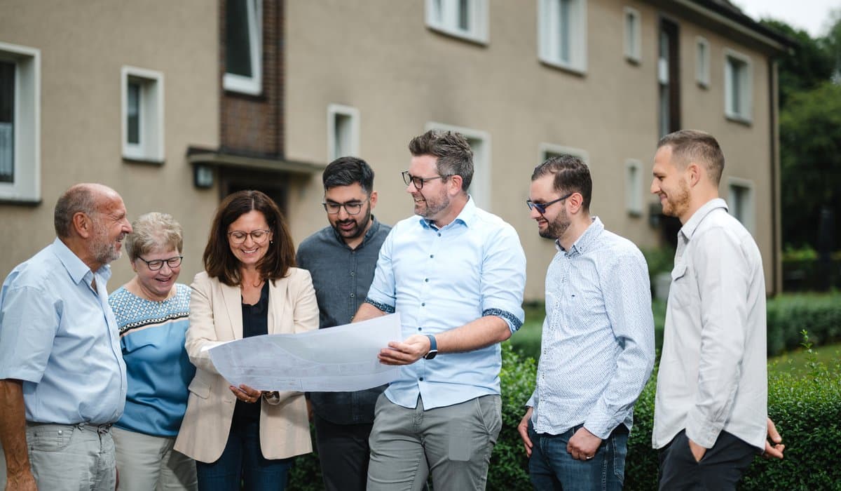 Projektteam für das Quartierskonzept steht vor einem Wohngebäude. Foto: Ludgar Staudinger