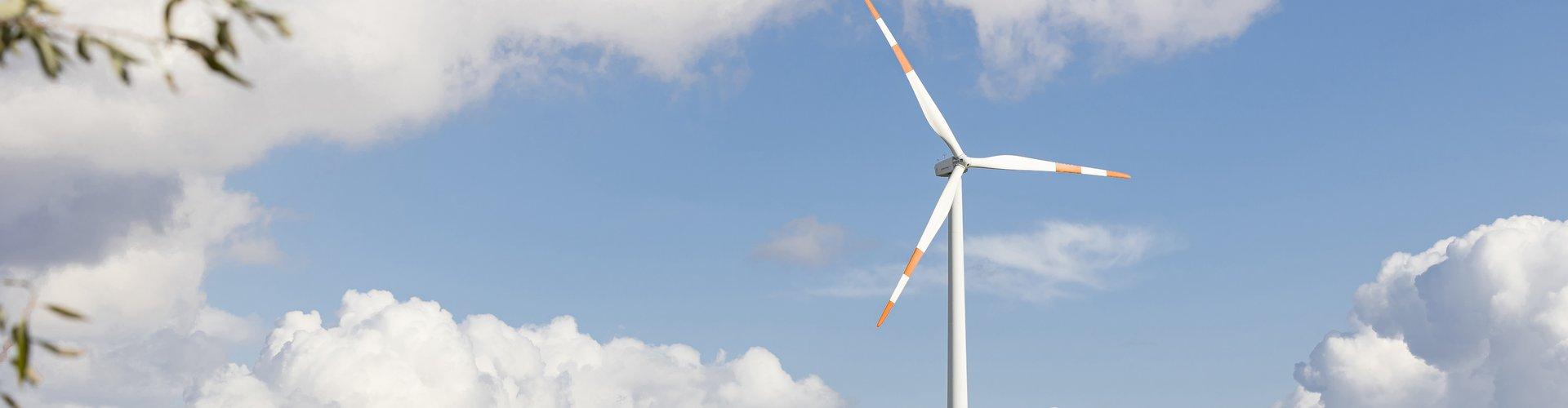 Windrad auf einem Feld mit bewölktem Himmel.